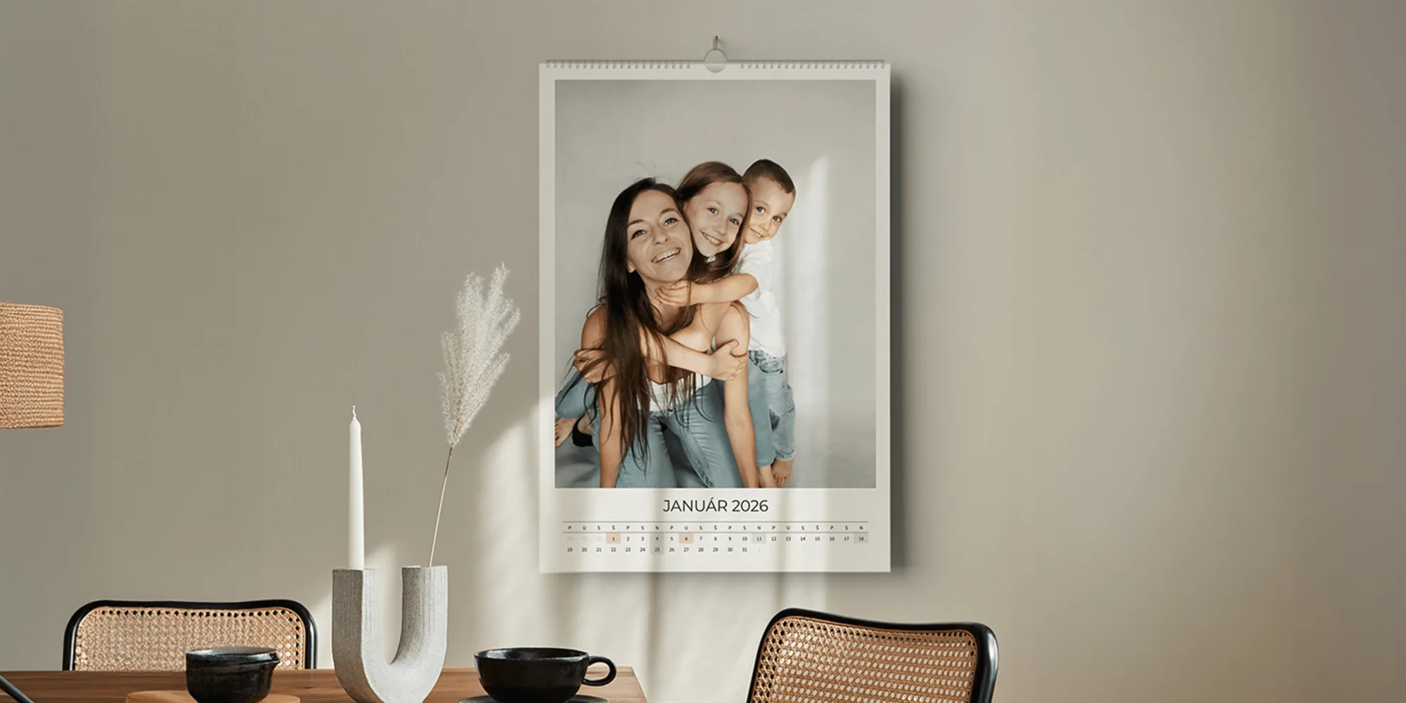 Nástenný fotokalendár s rodinnou fotografiou zavesený nad jedálenským stolom v svetlom interiéri