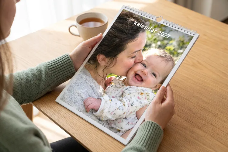 Žena drží nástenný fotokalendár s fotkou mamy a bábätka a nápisom Kalendár 2027